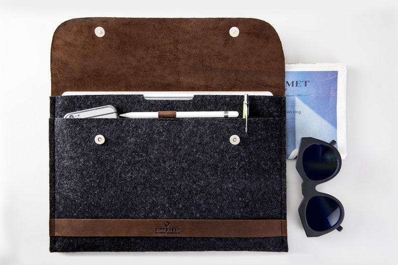 Leather and Felt laptop case open with Apple pencil in the loop. The case has CITYSHEEP logo embossed. Sunglases close to the csae.