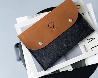 Op de afbeelding: Een grijze felt pouch met een bruine leren flap. De flap heeft een gegraveerd logo met de tekst "CITYSHEEP - Simple & Minimal".