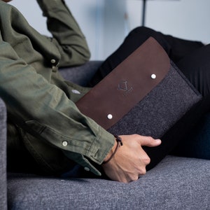 May include: A brown leather and gray felt laptop sleeve with a white logo that says "The Felt Co."