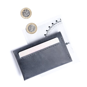 Gray leather wallet has a bank card sticking from it. Some coins near.