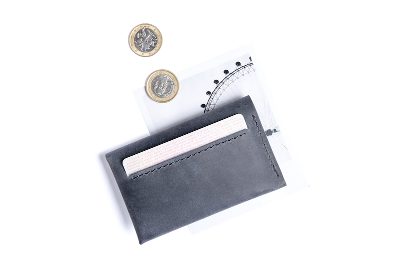 Gray leather wallet has a bank card sticking from it. Some coins near.