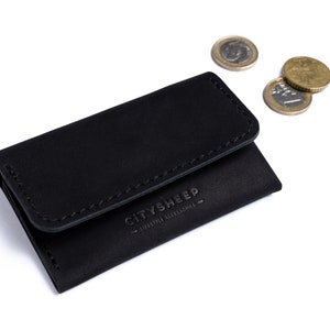 Minimalistic leather wallet with some coins. There is CITYSHEEP logo on it.