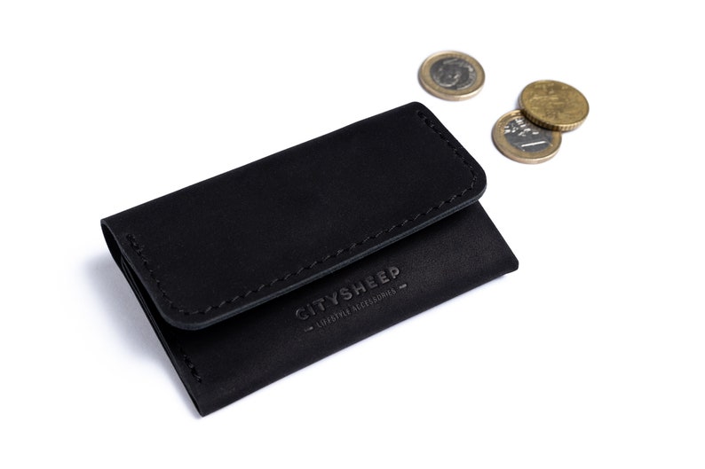 Minimalistic leather wallet with some coins. There is CITYSHEEP logo on it.