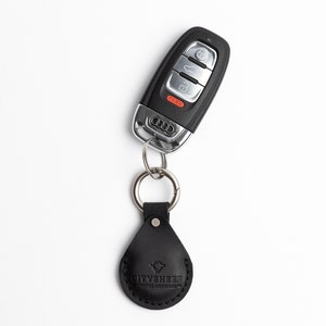 May include: Black Audi car key with a silver key ring and a black leather fob. The fob is stamped with the text "CITYSHEEP" and a logo. The key has buttons for lock, unlock, and panic.