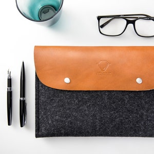 May include: A gray felt laptop sleeve with a brown leather flap and a snap closure. The flap has a logo that says "CitySheep" in a diamond shape.