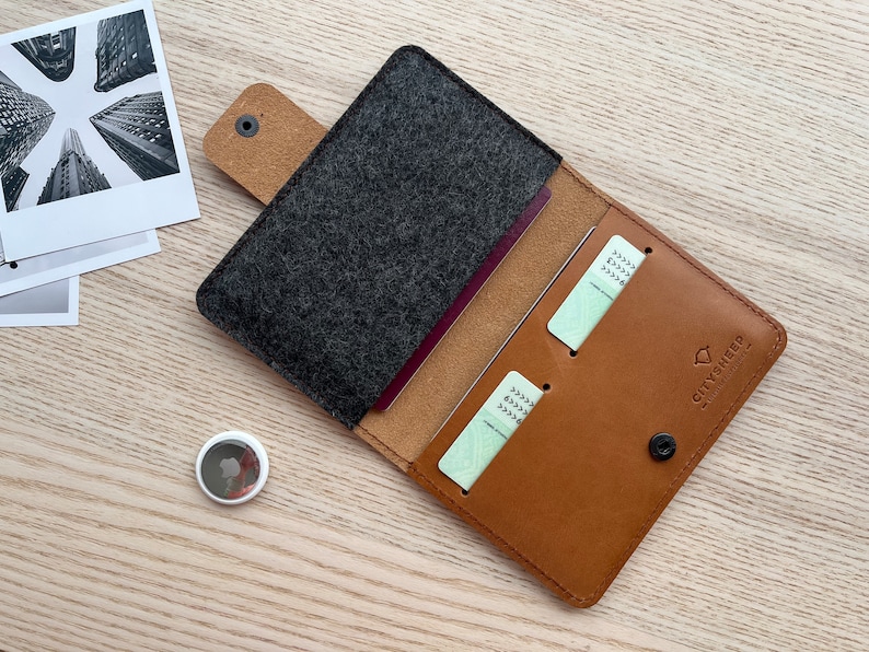 May include: A brown leather passport holder with a gray felt interior. The holder has two card slots and a snap closure. The brand name "CITYSHEEP" is printed on the front.
