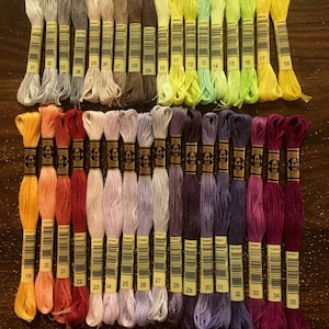 May include: A collection of 35 DMC embroidery floss skeins, arranged in rows of color gradients. The skeins are labeled with numbers 01 through 35.