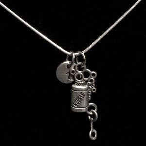 Puede incluir: Un collar de plata con un dije que dice "Bubble" y un pequeño círculo de plata con el número "7" en él.