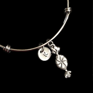 May include: A silver charm bracelet with a silver charm of a candy cane. The bracelet has a silver initial charm with the letter K.