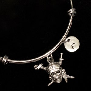 May include: Silver charm bracelet with a pirate skull charm, two crossed swords, and a silver charm with the letter 'F'.