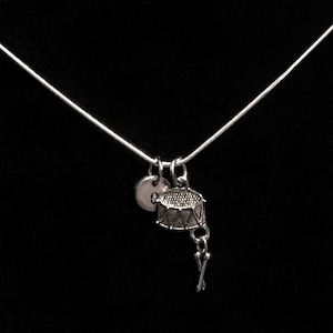 May include: A silver necklace with a small drum charm and a silver disc charm. The drum charm has a small pair of drumsticks attached to it.