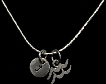 May include: A silver chain necklace with two charms. One charm is a round disc with the letter "J" engraved on it. The other charm is a stylized depiction of the astrological symbol for Aquarius.