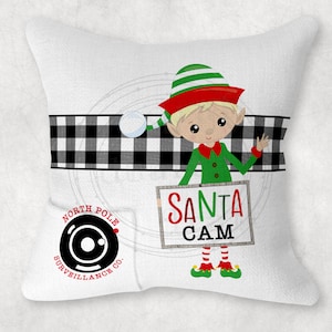 May include: White pillow with a black and white checkered pattern, a green elf holding a sign that says "Santa Cam", and a black and white circle with the words "North Pole Surveillance Co."