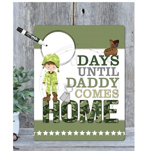 Può includere: Una lavagna bianca cancellabile a secco con un bordo a motivo di mimetica verde. La lavagna ha un cerchio nell'angolo in alto a sinistra per scrivere. La lavagna ha un cartone animato di un soldato al centro e il testo "DAYS UNTIL DADDY COMES HOME" al centro. La lavagna ha un motivo a stelle verdi nella parte inferiore.