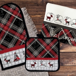 Pode incluir: Um conjunto de cozinha com um padrão xadrez vermelho, preto e cinza. O conjunto inclui uma luva de forno, um descanso de panela e um pano de prato. O pano de prato tem o texto "The Carsons" e uma fileira de renas.