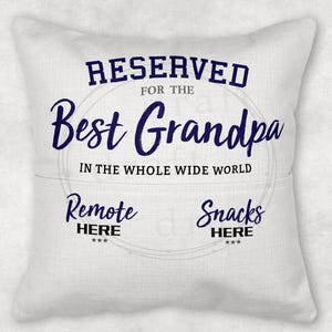 May include: White throw pillow with blue text that reads "RESERVED FOR THE BEST GRANDPA IN THE WHOLE WIDE WORLD". Below the text are two smaller sections that read "Remote HERE" and "Snacks HERE".