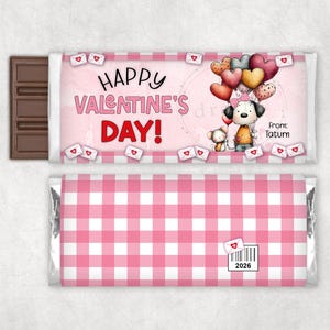 May include: A chocolate bar with a pink and white Valentine's Day themed wrapper. The wrapper features the text "Happy Valentine's Day!" and a cartoon dog holding heart-shaped balloons. The back of the wrapper has a pink gingham pattern.