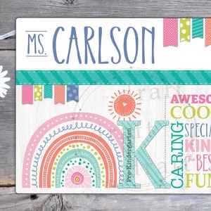 May include: A colorful classroom sign with the text "Ms. Carlson" and a large letter "K" for kindergarten. The sign features a rainbow, a sun, and the words "Awesome, Cool, Special, Kind, The Best, Fun, Caring, Wonderful".
