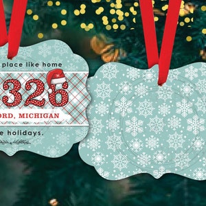 Puede incluir: Dos adornos navideños, uno con un patrón de copo de nieve y el otro con un patrón de cuadros rojos y blancos y el texto "There is no place like home 48326 WATERFORD, MICHIGAN for the holidays."