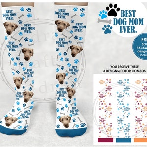 May include: Three pairs of white knee-high socks with a blue trim. Each sock features a repeating pattern of paw prints, bones, and a dog's face. The text "Best Dog Mom Ever." is printed on each sock. The socks are displayed on a white background with a text overlay that reads "You receive these 3 designs/color combos".