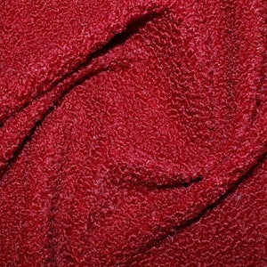 May include: Close-up of a deep red textured fabric with a slightly shiny finish.