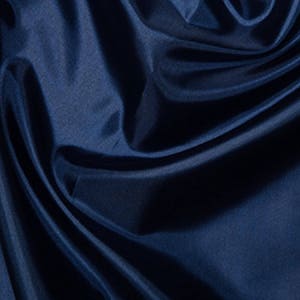 May include: A close-up of a deep blue fabric with a smooth, silky texture. The fabric is draped in soft folds, creating a luxurious and elegant look.
