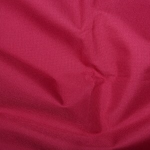 May include: A close-up of a smooth, solid, deep pink fabric. The fabric has a subtle texture and a slightly wrinkled appearance.