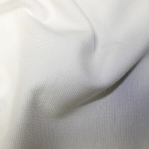 May include: White fabric with a textured surface. The fabric is smooth and soft.