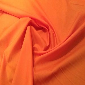 May include: A close-up of a bright orange fabric, folded and draped to show its texture and colour.