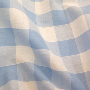 May include: A blue and white gingham fabric with a checkered pattern. The fabric is folded and has a soft, textured appearance.