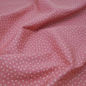 May include: A close-up of a pink fabric with a white polka dot pattern.