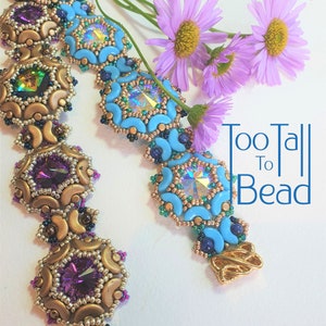 Könnte beinhalten: Zwei Perlenarmbänder, eines mit türkisfarbenen und goldenen Perlen, das andere mit violetten und goldenen Perlen. Die Armbänder liegen auf einem weißen Hintergrund mit lila Blumen. Der Text "Too Tall To Bead" befindet sich im Hintergrund.