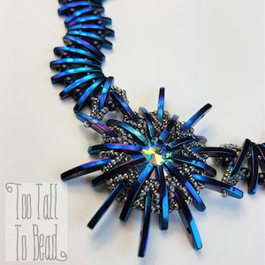 Könnte beinhalten: Eine blaue und silberne Perlenkette mit einem großen, sternförmigen Anhänger. Der Anhänger besteht aus Metallperlen und hat einen klaren Kristall in der Mitte.