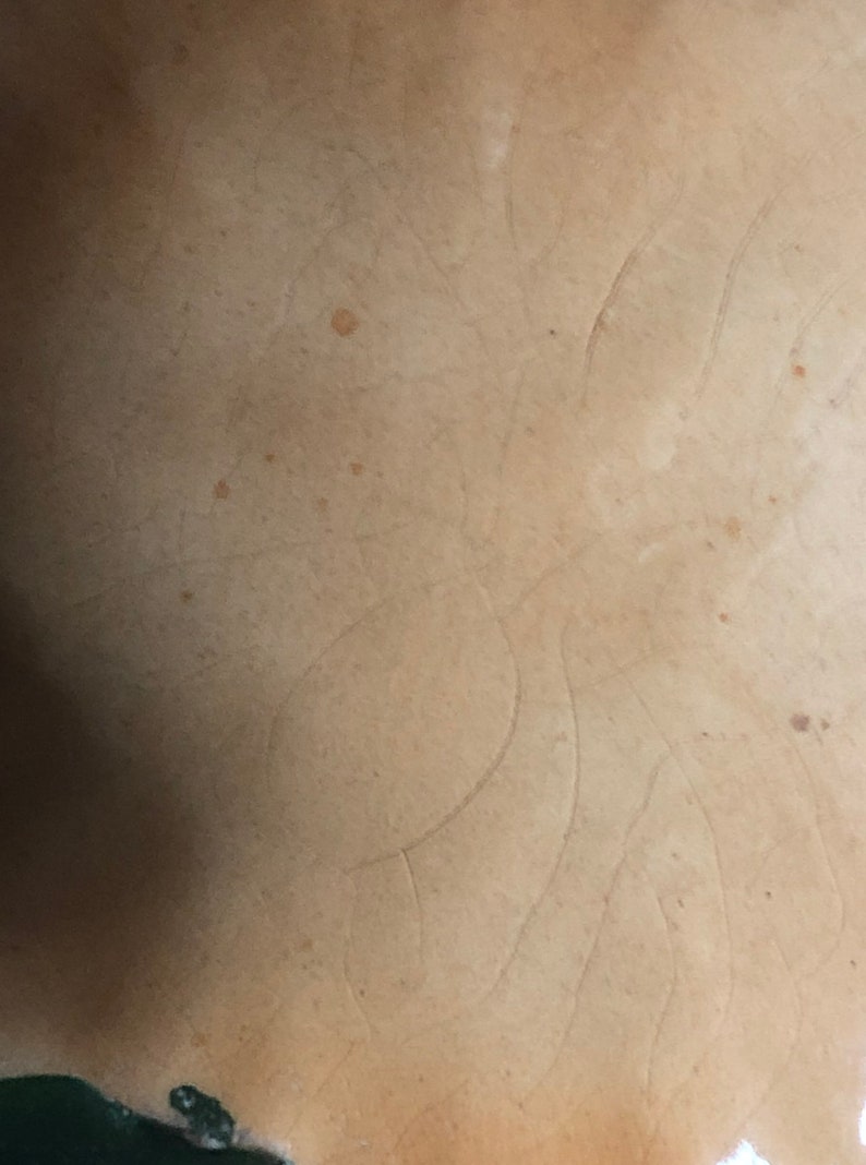 May include: Close-up of a light brown ceramic surface with a subtle pattern of lines and a few brown spots.