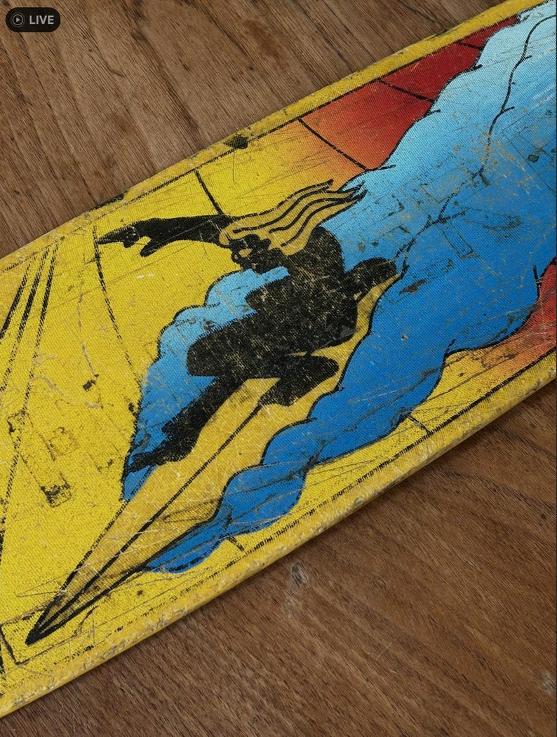 May include: A vintage skateboard deck featuring a black silhouette of a figure surfing a blue wave against a yellow and red background. The deck has a distressed, worn appearance.