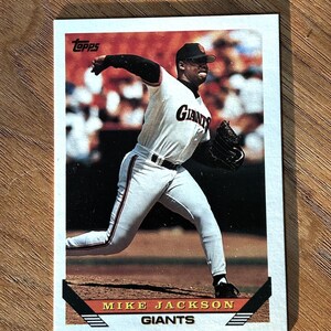 May include: A baseball card featuring Mike Jackson of the Giants. The card shows Jackson in a pitching pose, wearing a Giants uniform. The card has the Topps logo and the player's name and team at the bottom.