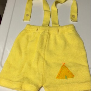 May include: Yellow knit shorts with suspenders and a small embroidered teepee design.