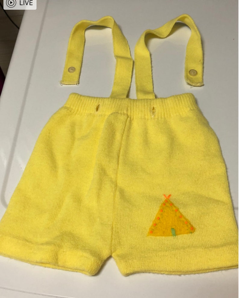 May include: Yellow knit shorts with suspenders and a small embroidered teepee design.