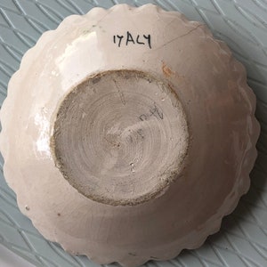 May include: White ceramic bowl with a scalloped edge and a brown glaze on the inside. The bottom of the bowl has the number "17 ACY" written in black.