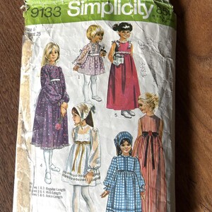 Op de afbeelding: Vintage Simplicity patroonhoes met illustraties van meisjes in jurken. De envelop is gelabeld "9133" en bevat maatdetails. De jurken zijn in verschillende stijlen en kleuren. Maten in centimeters.