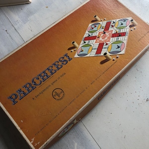 May include: A vintage game box for Parcheesi, a backgammon game of India, published by Selchow & Righter Company. The box is brown with blue and white text and a small image of the game board. The game board is colorful with red, blue, yellow, and green squares.