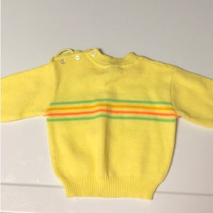 May include: A yellow knitted sweater with a striped pattern in green, orange, and pink.