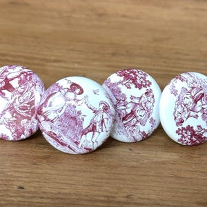 May include: Four white ceramic cabinet knobs with a burgundy toile design. Each knob features a different pastoral scene with figures, trees, and architectural elements. The knobs are round and have a smooth, glossy finish.