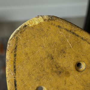 May include: Close-up of a yellow skateboard deck with two holes and a worn edge. The deck has a textured surface with black markings and the word "Explore" in a white box.