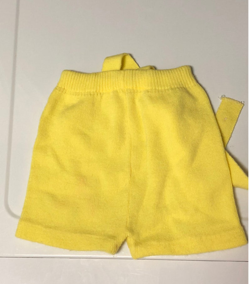 May include: Yellow knit shorts with a tie at the waist.