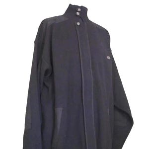 Peut inclure: Veste noire avec un col montant et des fermetures à boutons. La veste présente un design minimaliste avec des détails subtils, notamment des empiècements aux épaules et des poches. La veste est présentée sur un support sur fond blanc.