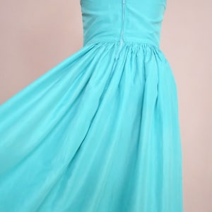 Peut inclure: Une robe maxi sans bretelles de couleur bleu turquoise vif. La robe a un corsage ajust&eacute; et une jupe ample.