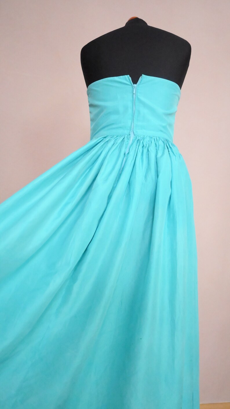 Peut inclure: Une robe maxi sans bretelles de couleur bleu turquoise vif. La robe a un corsage ajust&eacute; et une jupe ample.