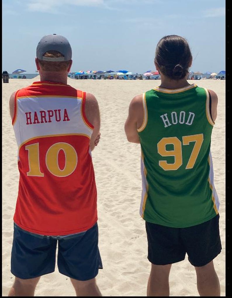 Puede incluir: Dos camisetas sin mangas vistas desde atr&aacute;s. La camiseta de la izquierda es roja y blanca con el texto HARPUA y el n&uacute;mero 10 en amarillo. La de la derecha es verde y blanca con el texto HOOD y el n&uacute;mero 97 en amarillo. Ambas tienen ribetes deportivos.