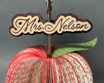 May include: A red book-shaped apple note holder with a green leaf and a wooden name tag that says "Mrs. Nelson".